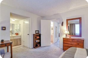 Une pièce comprenant un lit, une commode, un miroir et une porte donnant sur une salle de bain.