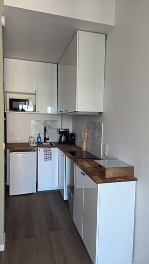 A compact kitchen with white cabinets, a microwave, a coffee maker, and a small refrigerator. - Beautiful, renovated duplex apartment in the countryside, just a stone's throw from the estuary's ports (Saint-Fort-sur-Gironde)