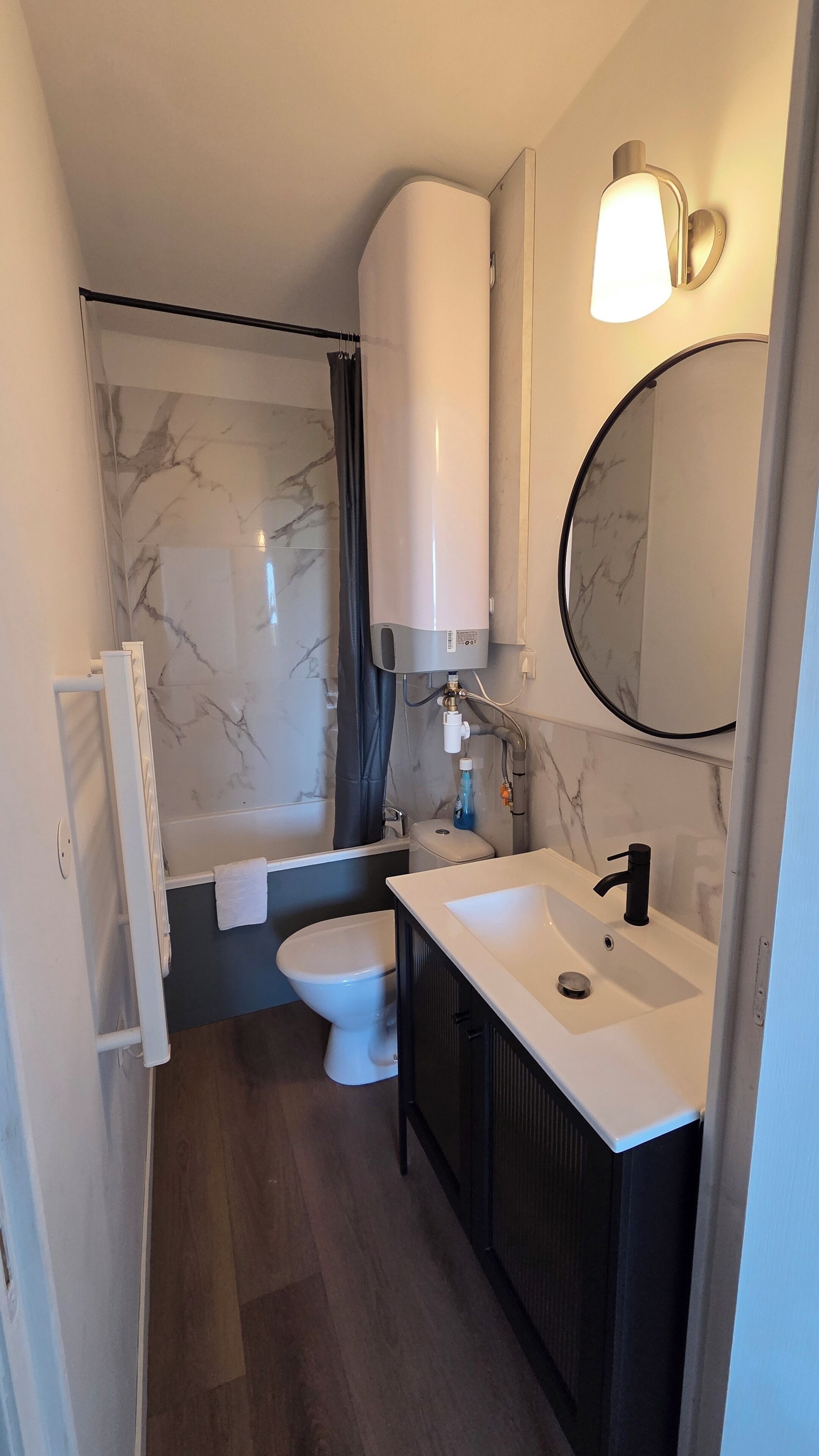 Pieni kylpyhuone, jossa on wc, pesuallas ja suihku.
