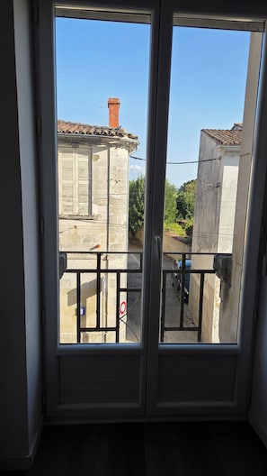A view from a balcony with a metal railing, overlooking a street with buildings and a parked car. - Beautiful, renovated duplex apartment in the countryside, just a stone's throw from the estuary's ports (Saint-Fort-sur-Gironde)