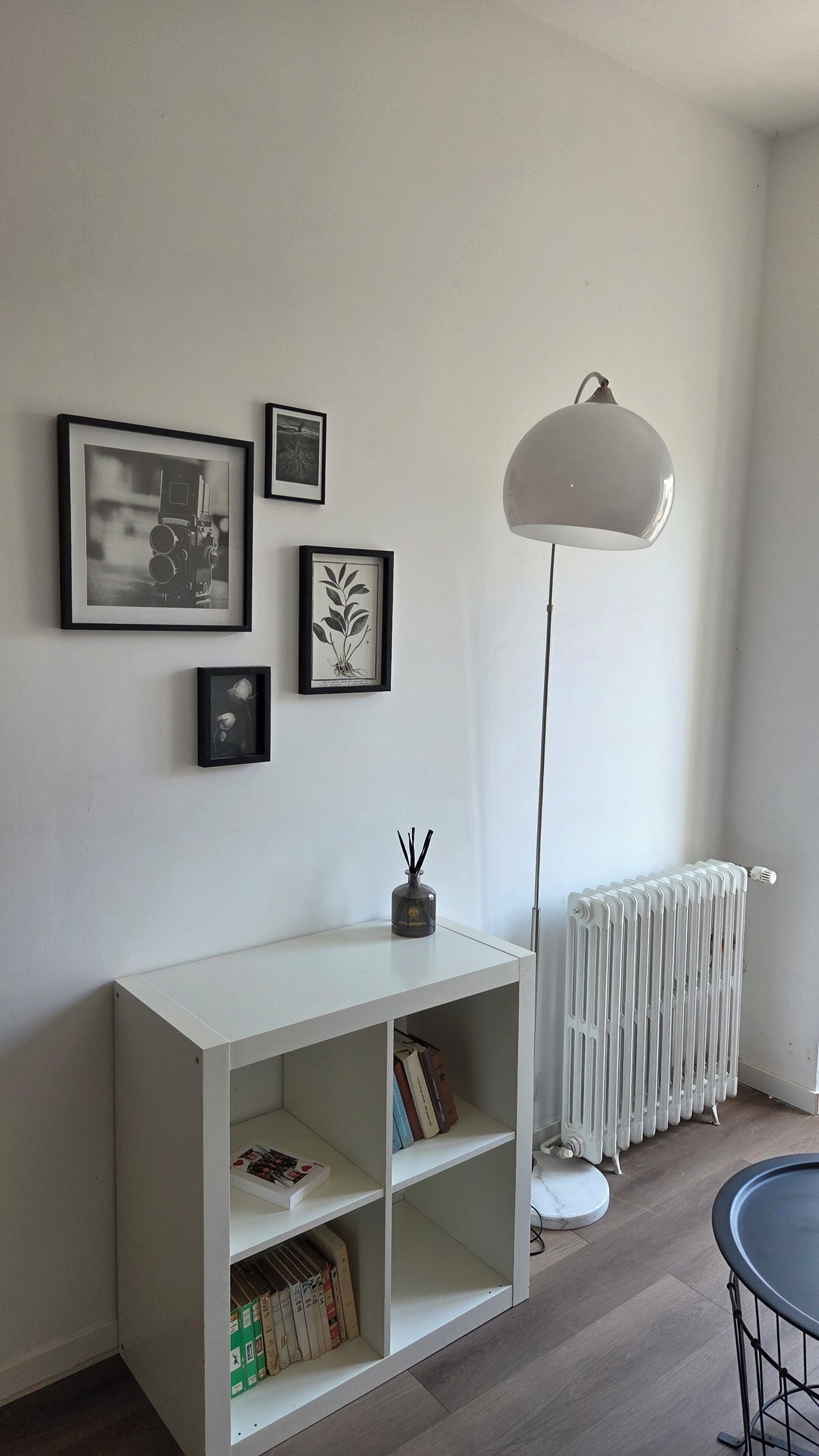 Ett rum med ett vitt konsolbord, ett element och en golvlampa.