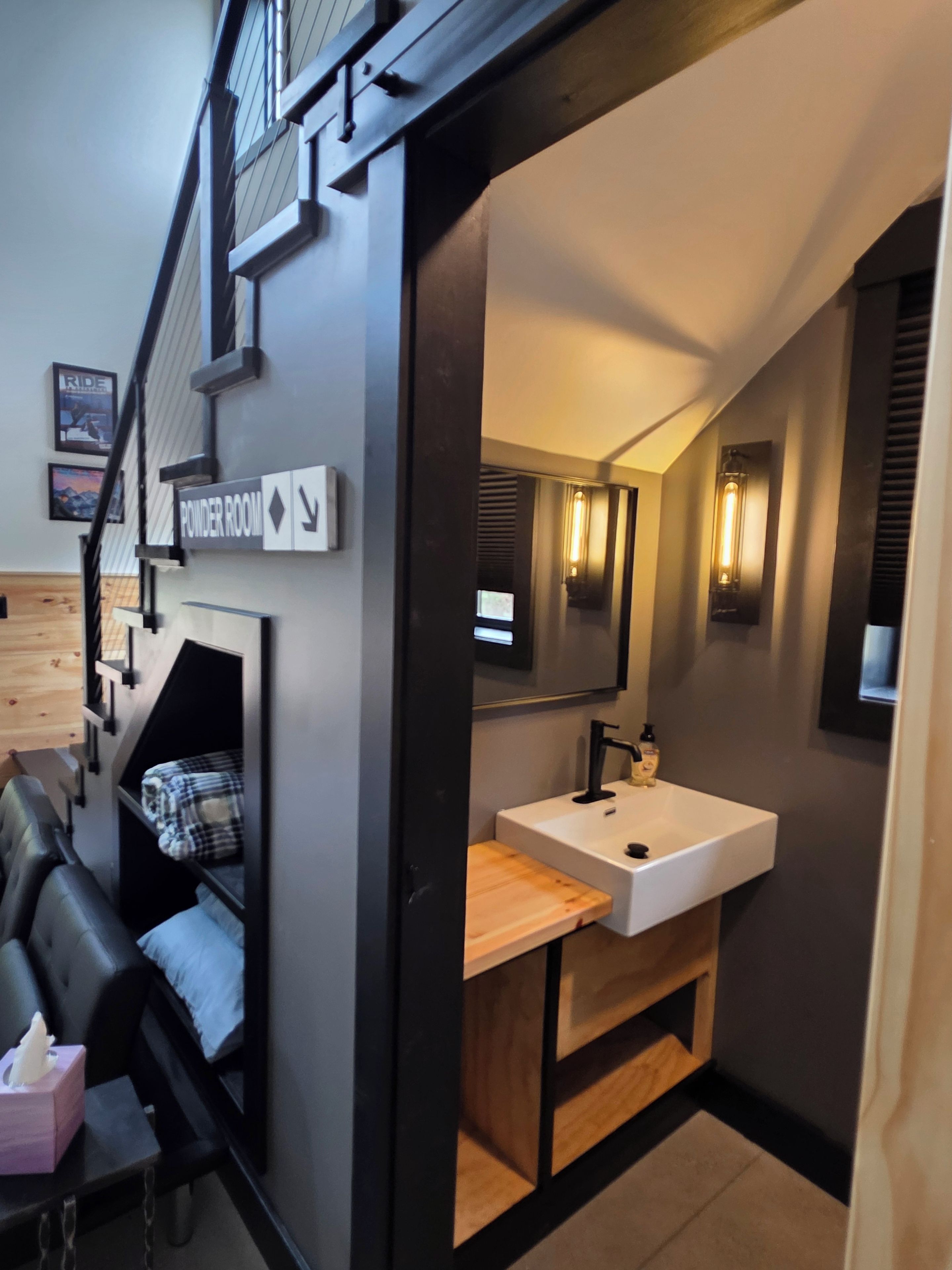 Een moderne badkamer met een wit wastafeltje, een houten opbergmeubel en een spiegel.
