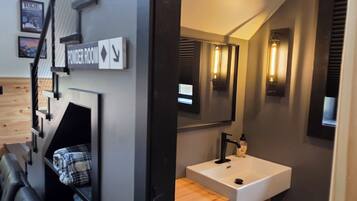 Een moderne badkamer met een wit wastafeltje, een houten opbergmeubel en een spiegel.