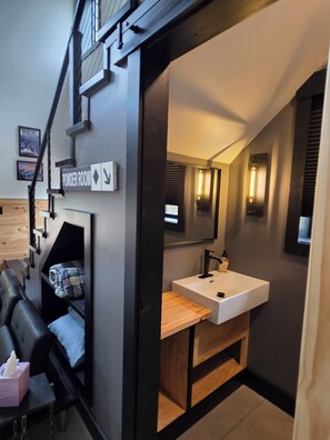 Een moderne badkamer met een wit wastafeltje, een houten opbergmeubel en een spiegel.