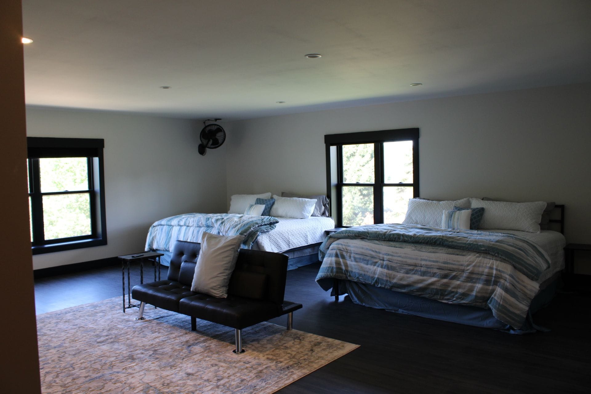 A bedroom with two beds, a sofa, and a fan.