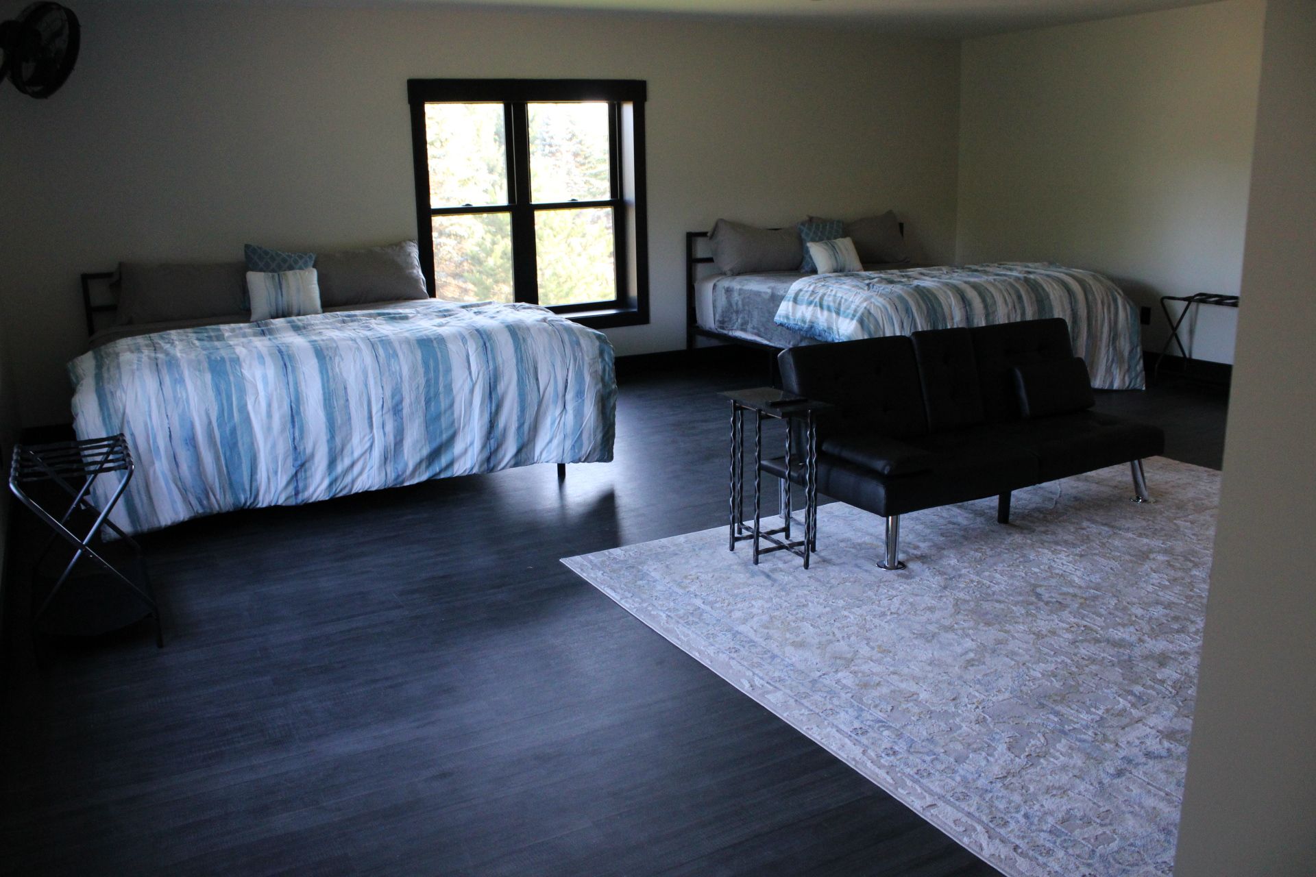 A bedroom with two beds, a black sofa, and a small table.