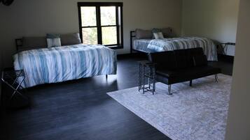 A bedroom with two beds, a black sofa, and a small table.