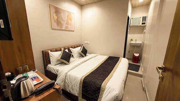 A hotel room with a bed, bedside table, and a painting on the wall.