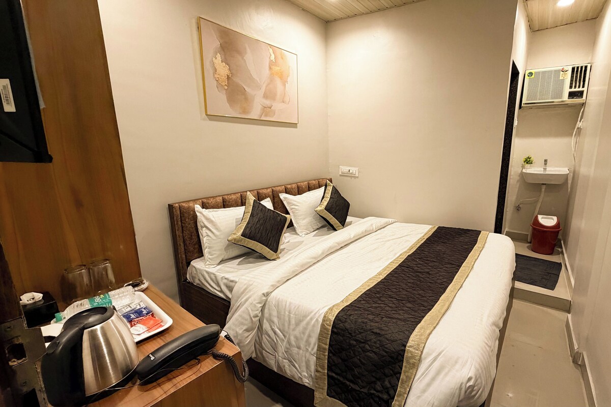 A hotel room with a bed, bedside table, and a painting on the wall.