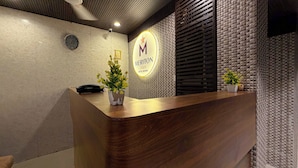 A hotel reception desk with a wooden finish, a clock, and a sign indicating 'Meriton Star Hotel Rooms'.