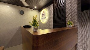 A hotel reception desk with a wooden finish, a clock, and a sign indicating 'Meriton Star Hotel Rooms'. - Hotel Meriton Star  (Ulhasnagar)