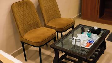 Habitación con dos sillones tapizados y una mesa de vidrio con varios objetos encima.
