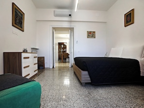 A bedroom with a bed, a dresser, a chair, and a door leading to a bathroom. - Vanella Luxury Apartment Rome (Roma)