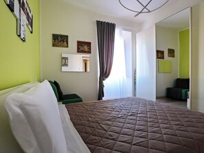 A hotel room with a large bed, a green wall, and a mirror. - Vanella Luxury Apartment Rome (Roma)