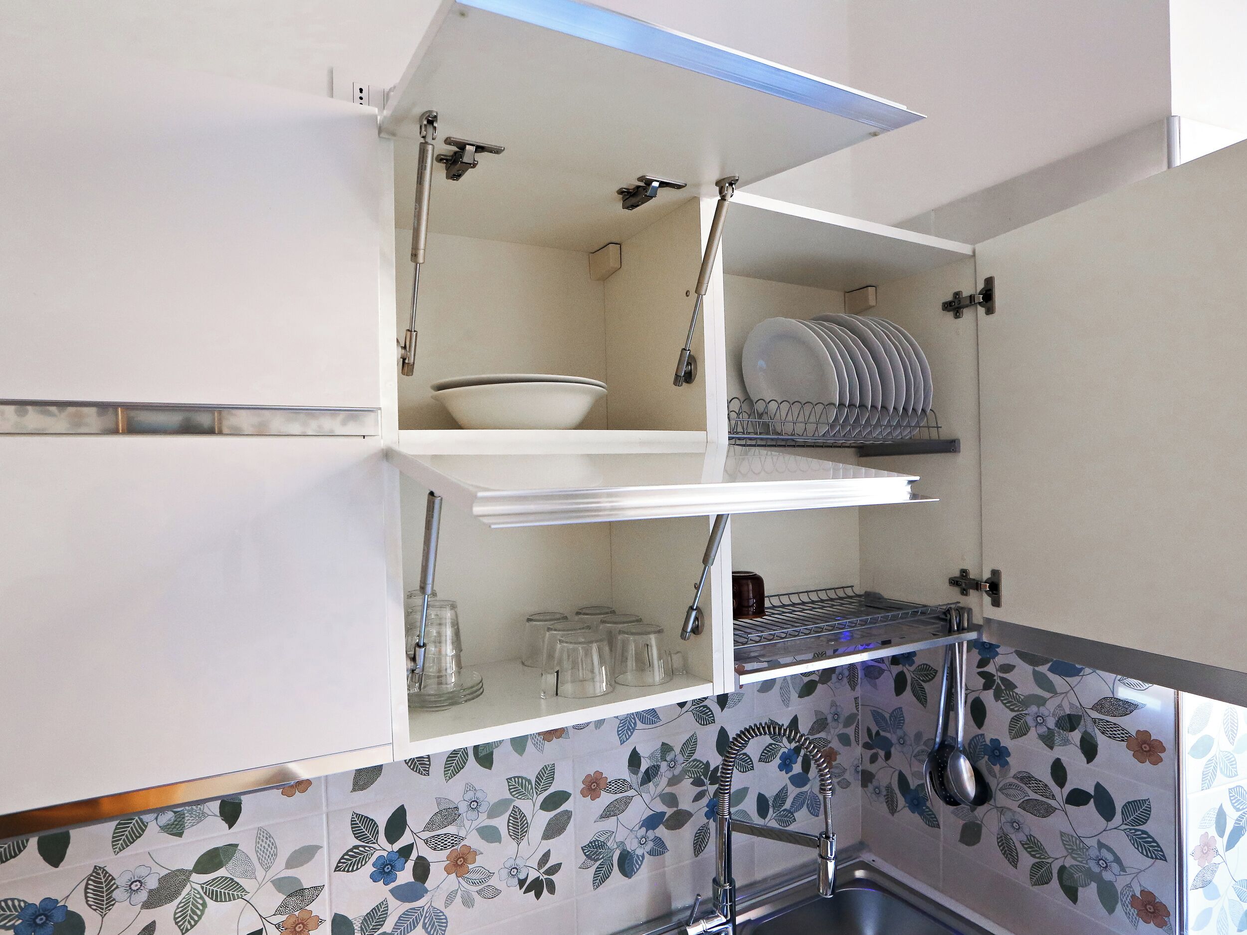 A kitchen with a white cabinet, a dish rack, and a sink.