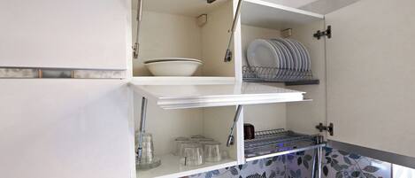 A kitchen with a white cabinet, a dish rack, and a sink.