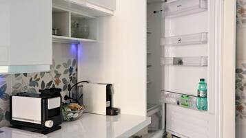 A kitchen with a built-in microwave, a toaster, and a refrigerator with a water bottle inside.