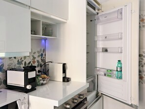 A kitchen with a built-in microwave, a toaster, and a refrigerator with a water bottle inside. - Vanella Luxury Apartment Rome (Roma)