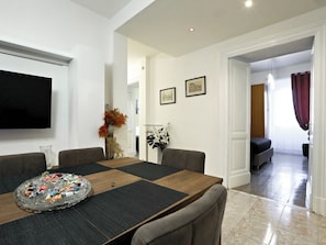 A dining area with a large table, chairs, a television, and framed pictures on the wall. - Vanella Luxury Apartment Rome (Roma)