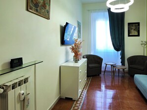A living room with a flat-screen TV, a sofa, a chair, a small table, and a decorative vase. - Vanella Luxury Apartment Rome (Roma)