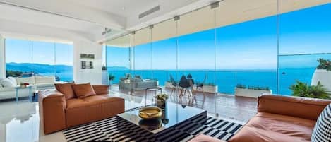 Un salon moderne doté d’une grande baie vitrée donnant sur la mer.