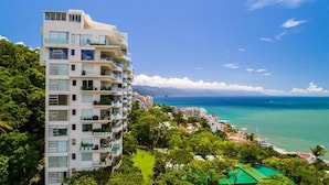 Un hotel de varios pisos con balcones, una piscina y vista al océano.