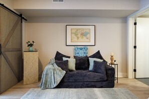 Ein modernes Wohnzimmer mit einem dunkelgrauen Sofa, einer Weltkarte an der Wand und einem kleinen runden Tisch mit einer Kerze.