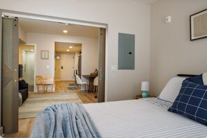 A bedroom with a bed, a nightstand, a lamp, and a wall-mounted shelf. - Stylish Fishtown 1BR - Prime Location (Philadelphia)