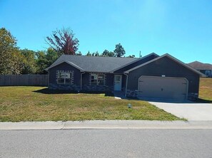 A two-story house with a garage, a front lawn, and a clear sky. - Liberty INN- 4Beds- near Fort-Leonard-Wood (Waynesville)