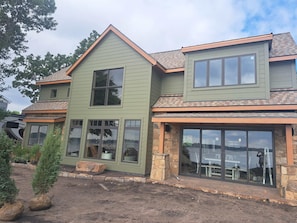 Et toetagers hus med stensokkel, store vinduer og en grøn facade.