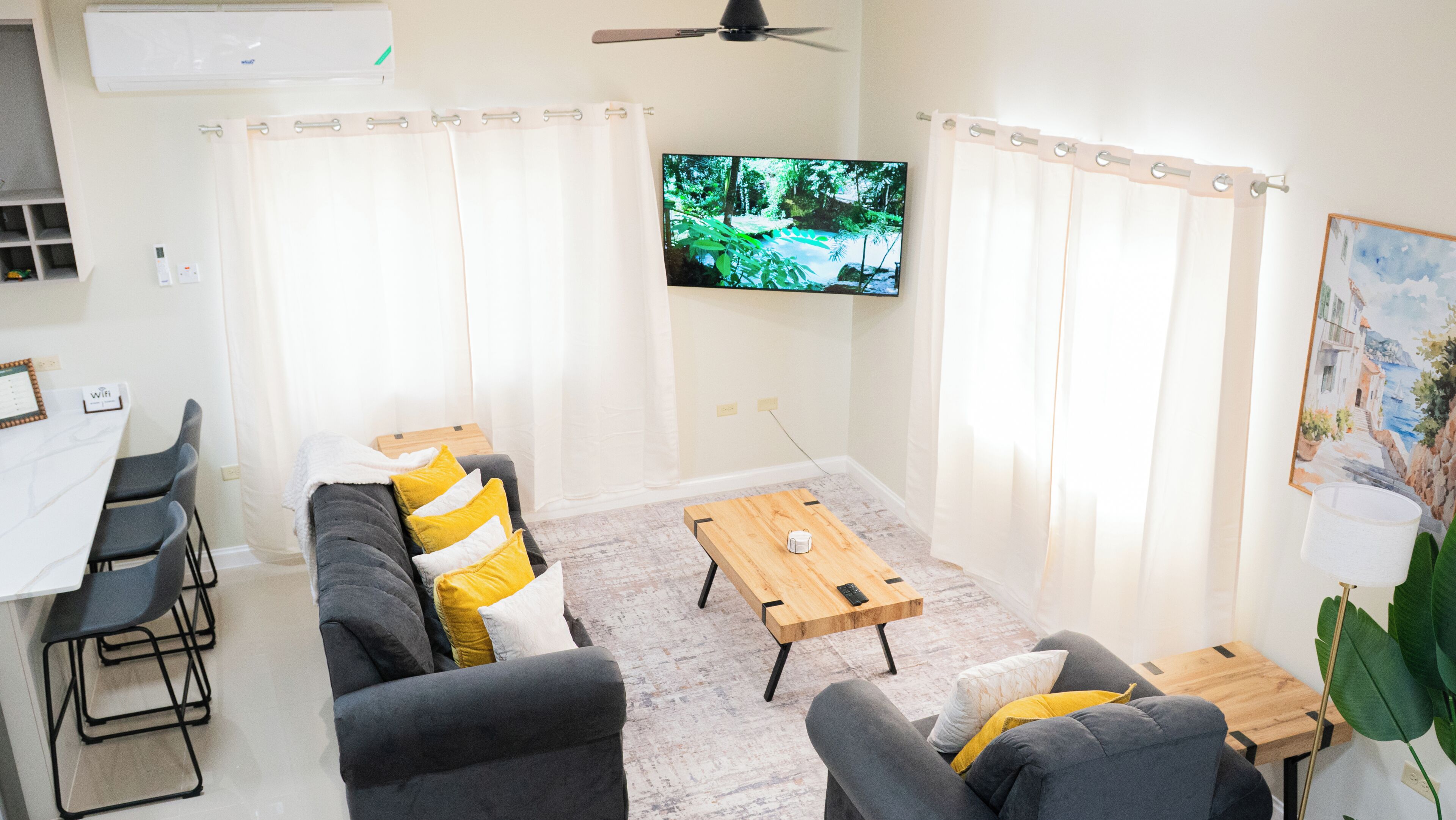 Ein Wohnzimmer mit einer Couch, einem Couchtisch und einem Fernseher. Es gibt einen Essbereich mit Stühlen und einem Tisch.