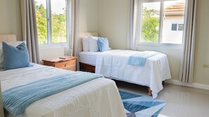 A bedroom with two beds, a nightstand, and a window with curtains. - Beautiful 3-bedroom house with AC in charming Ocho Rios (Ocho Rios)