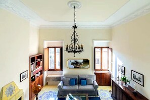 A living room with a chandelier, a sofa, a coffee table, and a fireplace. - Historic Via Giulia Loft by Flatinrome (ROMA)