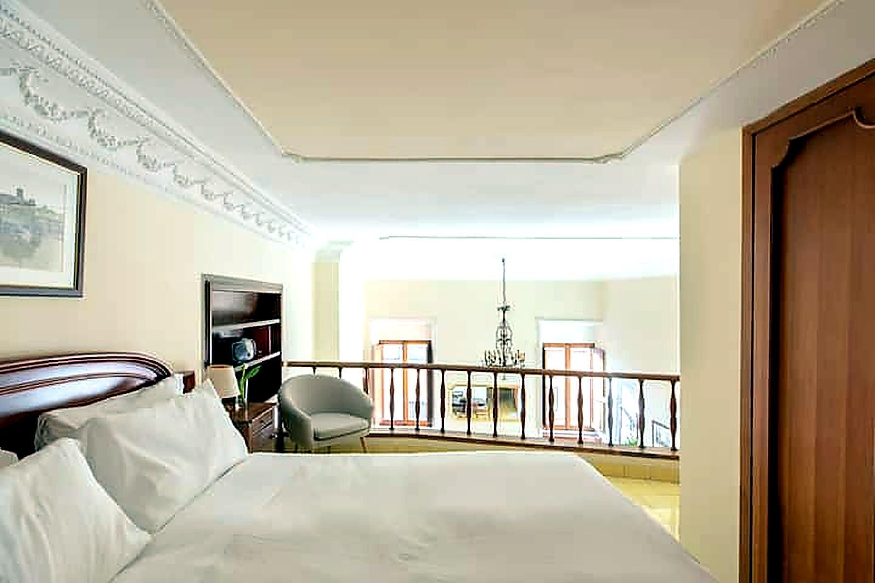 Une chambre d’hôtel comprenant un lit, un bureau, une chaise, une télévision et un balcon avec une rambarde.