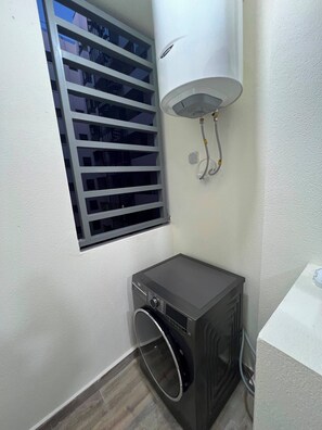 A compact room with a built-in washer and dryer, a window with blinds, and a white wall. - Fabulous 3-bedroom, 2 bathroom apartment with free parking in vibrant Tanger (Tanger)