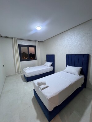 A hotel room with two single beds, a large window, and a ceiling light. - Fabulous 3-bedroom, 2 bathroom apartment with free parking in vibrant Tanger (Tanger)