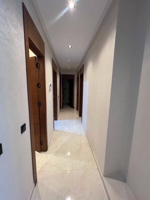 A corridor with a tiled floor and wooden doors on one side. - Fabulous 3-bedroom, 2 bathroom apartment with free parking in vibrant Tanger (Tanger)