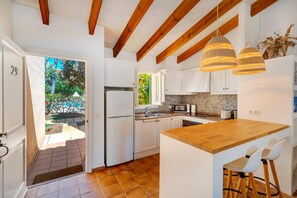 Una cocina moderna con armarios blancos, una isla de madera y lámparas colgantes.