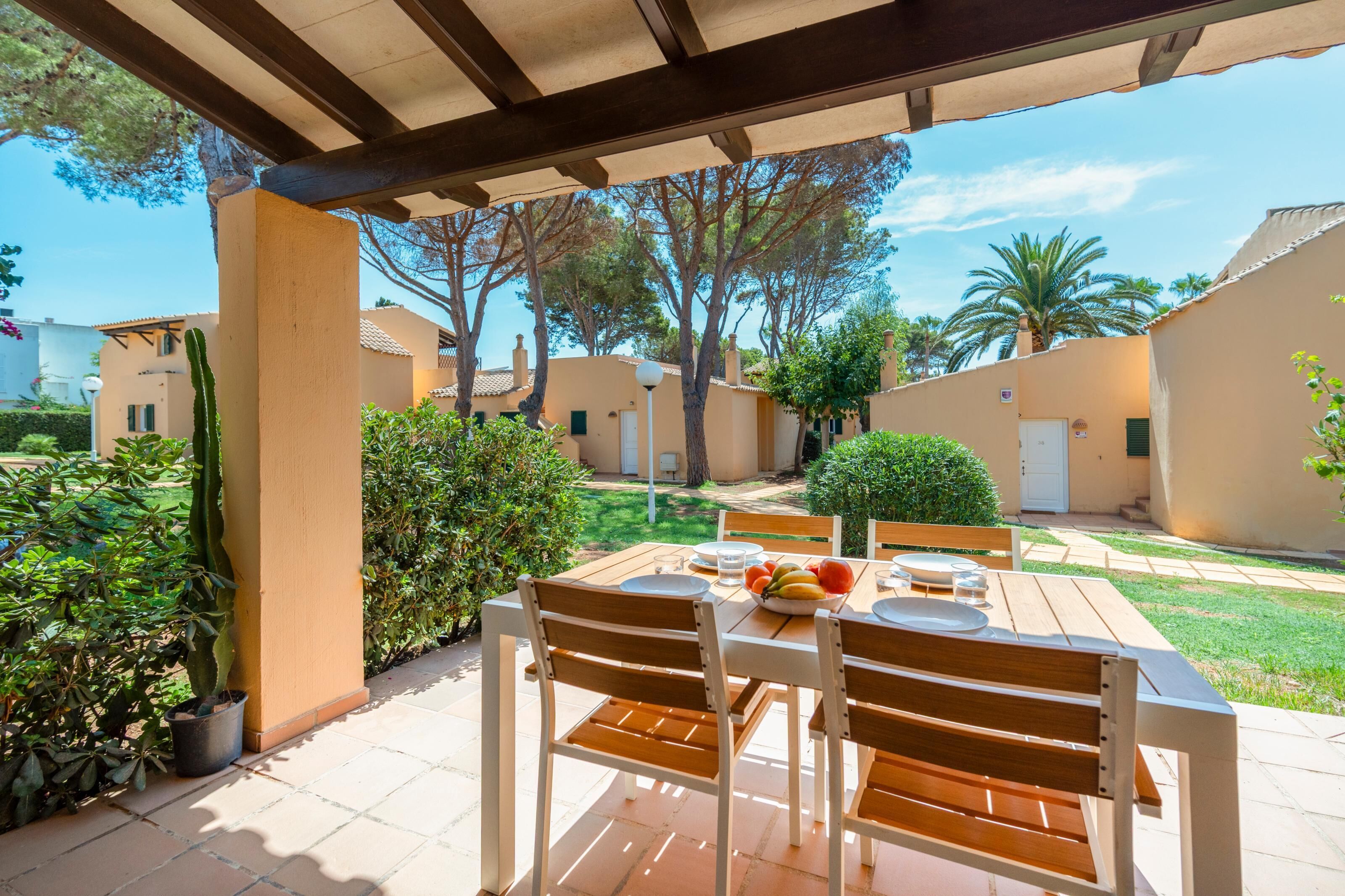 An outdoor patio with a table set for dining, surrounded by greenery and a clear view of the neighborhood.