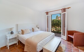 A bedroom with a bed, bedside tables, a bench, and a view of the outdoors. - Casa Massieu - Relax steps from the beach (Ciutadella de Menorca)