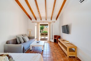 Un espacio habitable compacto con sofá, una mesita, televisión instalada en la pared y un banco.