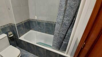 A bathroom with a toilet, bathtub, and shower curtain.