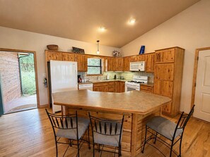 A kitchen with wooden cabinets, a central island, and a built-in oven. - Peaceful Redwood Retreat Cabin with Hot Tub & Incredible Forest Views (Ruidoso)