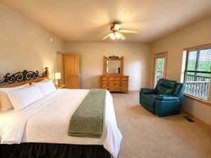 A bedroom with a bed, dresser, chair, and a ceiling fan. - Peaceful Redwood Retreat Cabin with Hot Tub & Incredible Forest Views (Ruidoso)