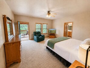 A bedroom with a bed, a chair, a television, and a ceiling fan. - Peaceful Redwood Retreat Cabin with Hot Tub & Incredible Forest Views (Ruidoso)
