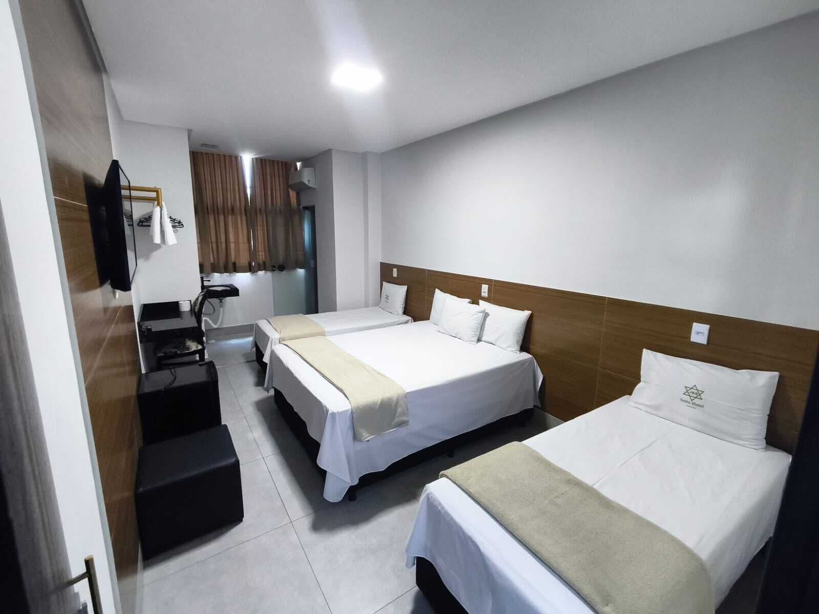A hotel room with two beds, a desk, and a mirror.