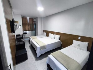 Una camera d'albergo con due letti, una scrivania e uno specchio.