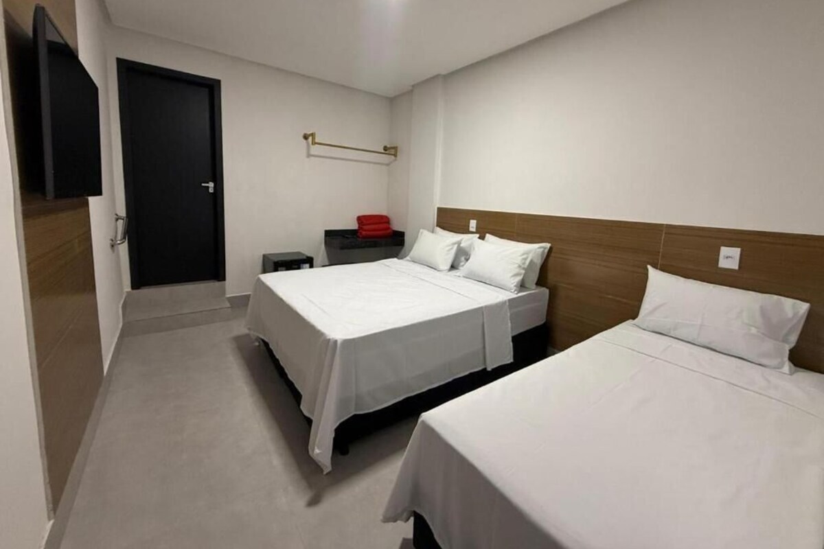Una camera d'albergo con due letti, una televisione a schermo piatto, un piccolo tavolo e una porta.