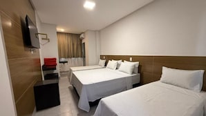 Habitación de hotel con dos camas, un televisor de pantalla plana montado en la pared y un escritorio con una silla.