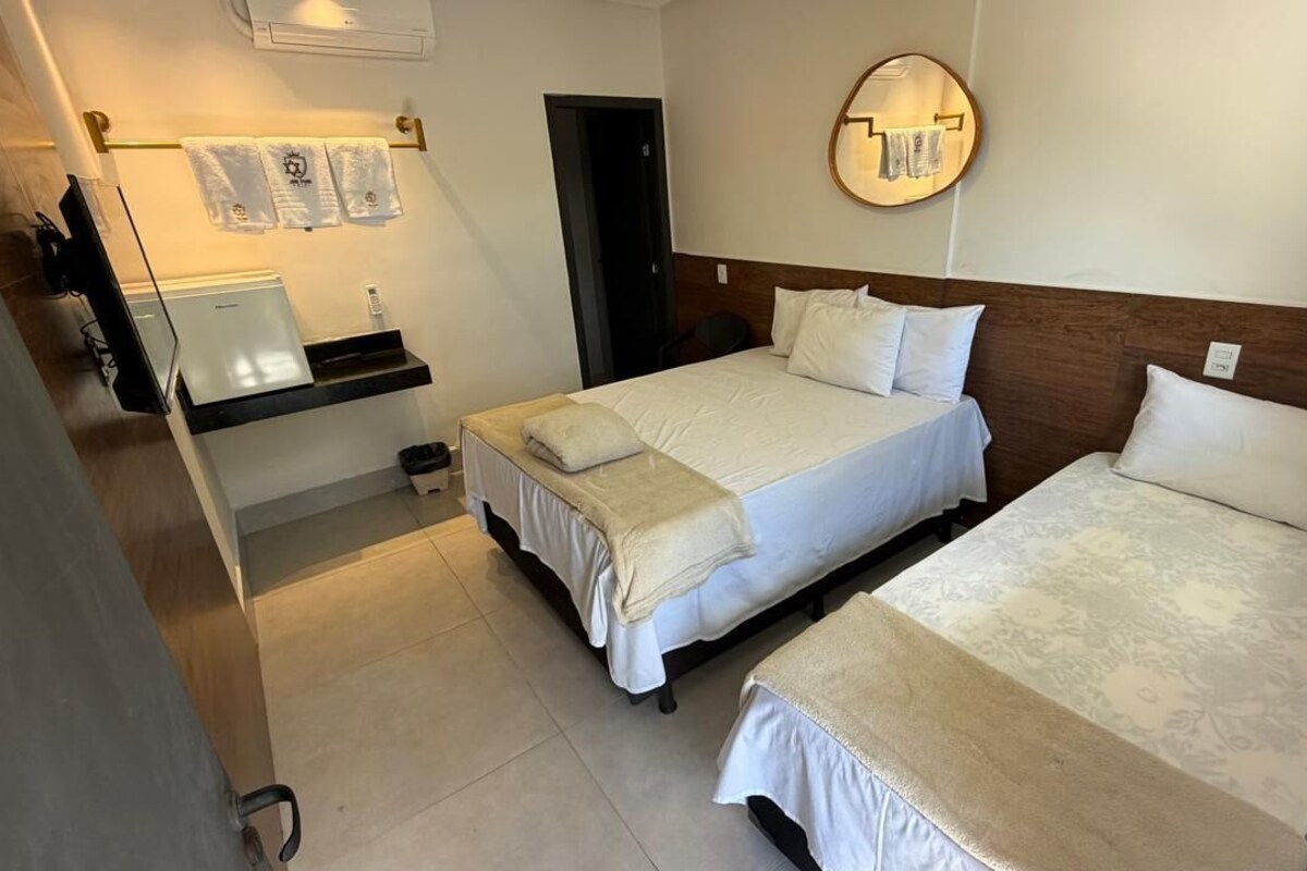 Una camera d'albergo con due letti, una scrivania con un computer, uno specchio e un portasciugamani.